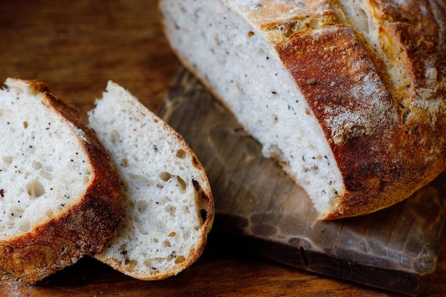 Una pagnotta di pane fresco fatto in casa e pezzi affettati giacciono su un tavolo di legno Utile cottura senza lievito con le proprie mani