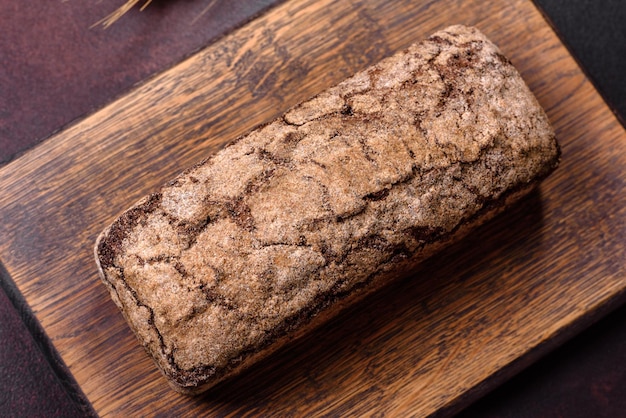 Una pagnotta di pane integrale con chicchi di cereali su un tagliere di legno