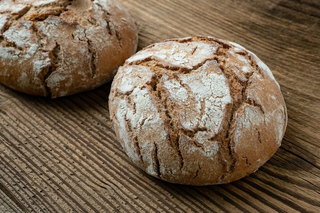 Una pagnotta rustica appena sfornata di pane su un vecchio tavolo di legno