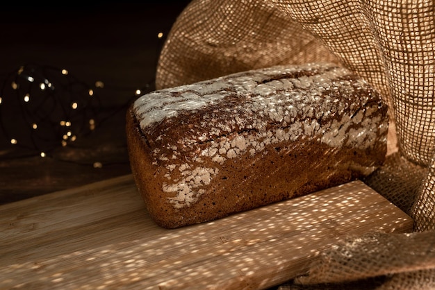 Una pagnotta su una tavola di bambù, cosparsa di fiocchi d'avena, in un sacchetto di juta con ghirlande