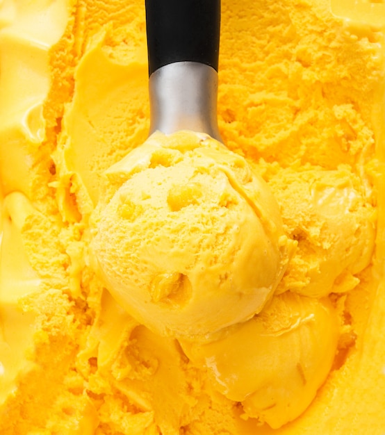 Una pallina di gelato al mango naturale in una scatola. Sfondo di gelato arancione tropicale