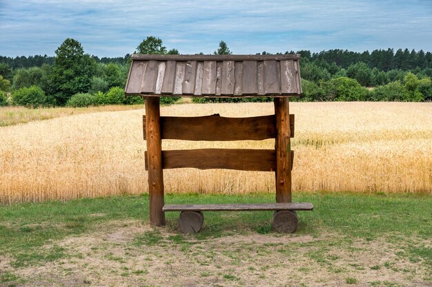 Una panca gazebo in legno in un campo di grano