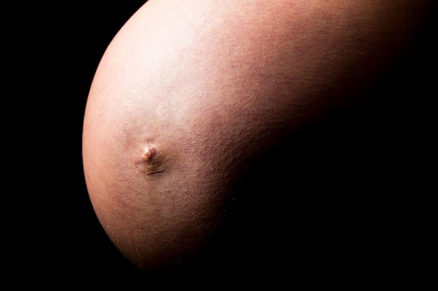 Una pancia di donna incinta su sfondo nero. Scattata in Studio con una 5D mark III.