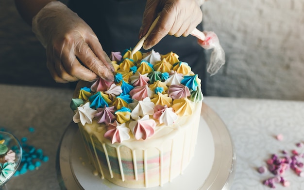 Una pasticcera fa una torta nuziale con le sue mani e applica decorazioni colorate sulle torte con la crema