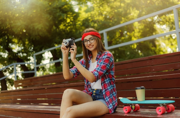 Una pattinatrice divertente vestita con abiti eleganti siede sugli spalti nello skatepark