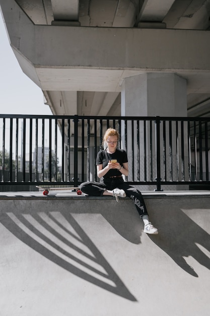 Una pattinatrice europea con i capelli rossi sta cavalcando uno skateboard su uno skate pad una donna in nero