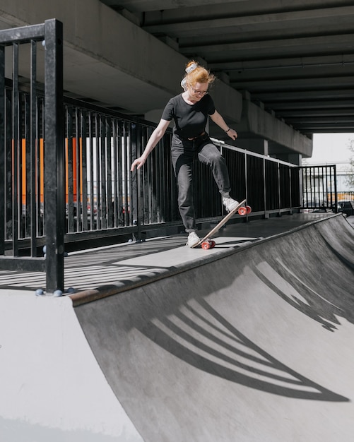 Una pattinatrice europea con i capelli rossi sta cavalcando uno skateboard su uno skate pad una donna vestita di nero