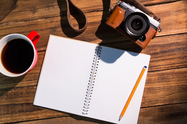 Una penna sul blocco note accanto alla tazza di caffè e fotocamera