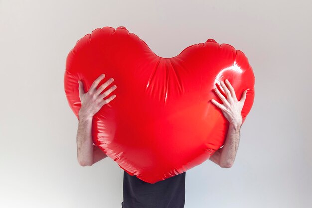 Una persona abbraccia un grande cuore gonfiabile rosso d'amore Concetto di salute e amore