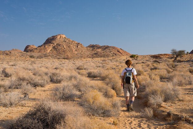 Una persona che fa un'escursione nel deserto di Namib, parco nazionale di Namib Naukluft, Namibia. Avventura ed esplorazione in Africa. Cielo blu chiaro.