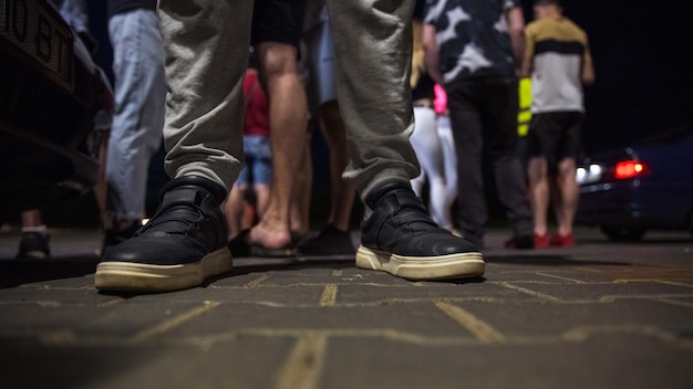 Una persona che indossa un paio di scarpe da ginnastica nere si trova in mezzo alla folla.