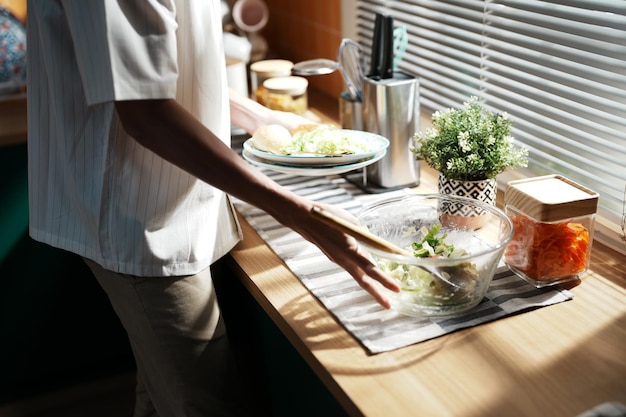 Una persona che prepara il cibo in una cucina con una pianta in vaso sul bancone.