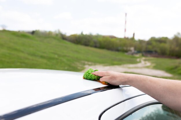 Una persona che pulisce un'auto con un panno verde.