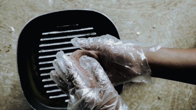 Una persona che pulisce una padella con un guanto sulla mano.