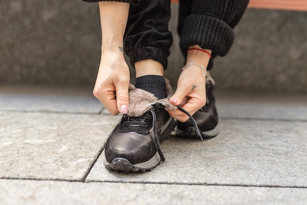 Una persona che si allaccia le scarpe su un marciapiede