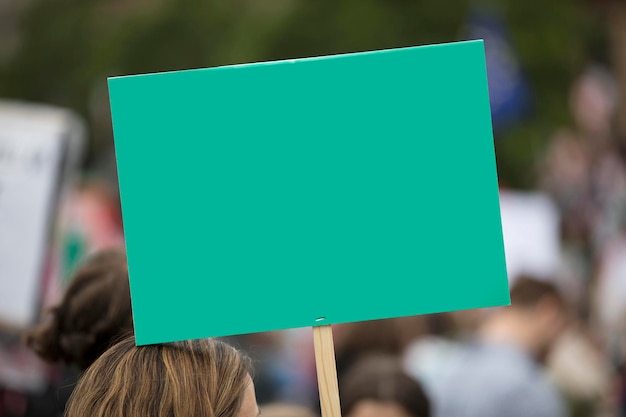 Una persona che tiene uno striscione di protesta verde vuoto a una manifestazione politica