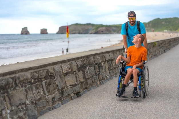 Una persona disabile in sedia a rotelle spinta da un amico sulla spiaggia che si diverte in estate