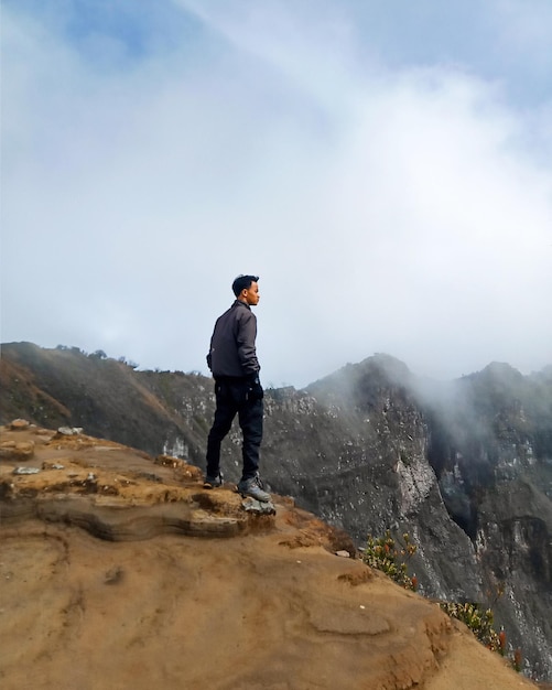 una persona in piedi sulla cima di una montagna sull'orlo di una scogliera