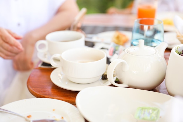 Una persona seduta a un tavolo con una tazza di tè e un piatto di cibo.