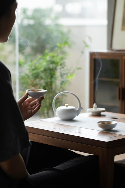 Una persona siede a un tavolo con una teiera e una tazza di tè Bevendo tranquillamente il tè al mattino