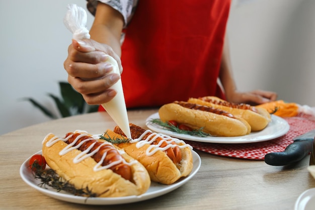 una persona sta tenendo una forchetta e un piatto di hot dog con ketchup e senape