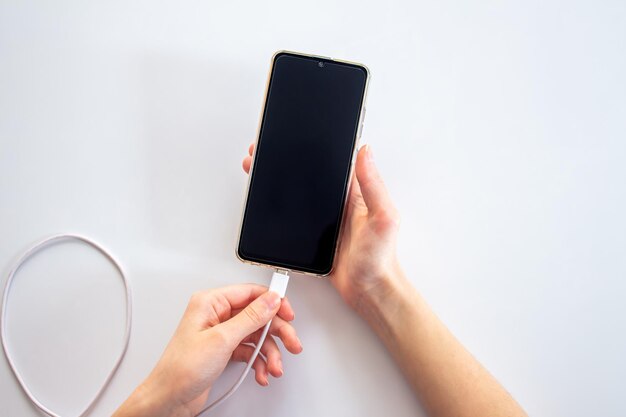 Una persona tiene in mano un telefono con un cavo nero collegato.