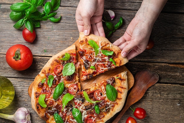 Una persona tiene in mano una pizza da cui è stata estratta una fetta.