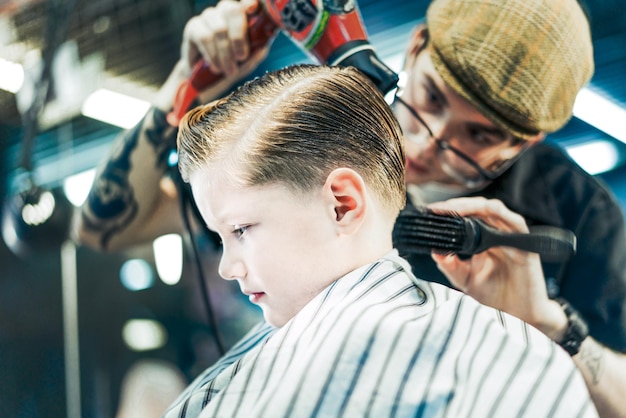 Una pettinatura per un ragazzo è lo styling con una spazzola e un asciugacapelli