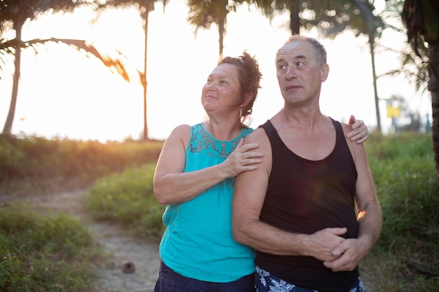 Una piacevole e deliziosa donna matura e un uomo che si crogiolano alla calda luce del sole stanno insieme in giugno tropicale