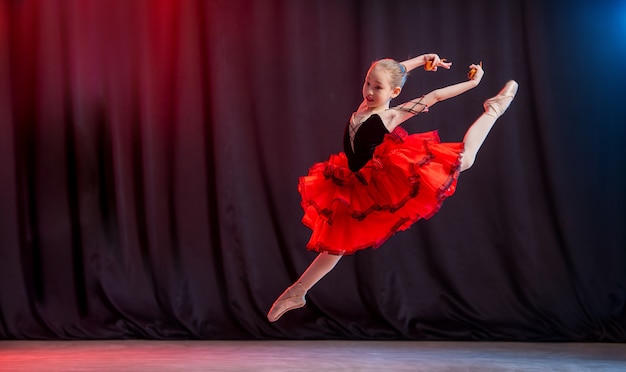 Una piccola ballerina balla sul palco in un tutù di balletto su scarpe da punta con scarpe castane, congelato in volo, una classica variazione di Kitri.