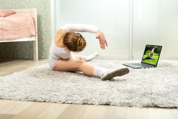 Una piccola ballerina in costume da bagno bianco balla a casa impara a ballare a distanza Lezioni di ballo a casa Lezioni di ballo online