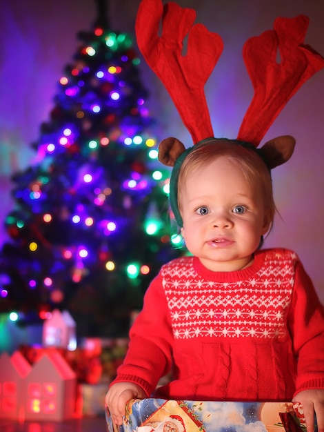 Una piccola bambina, con le corna di cervo di Natale, si trova in una confezione regalo