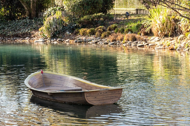 Una piccola barca a remi in legno galleggia su acque calme con canne nell'acqua I riflessi della barca sono visibili nell'acqua