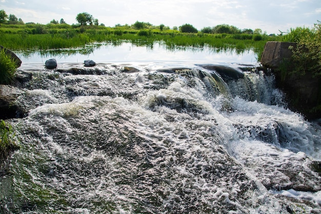 Una piccola cascata di fiume in una luminosa giornata estiva di sole