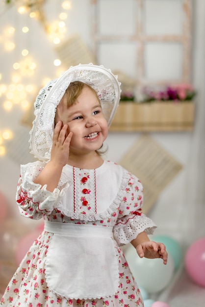 Una piccola e bella ragazza con un vestito da bambola e un cappello