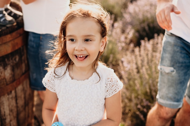 Una piccola ragazza affascinante che posa in un campo di lavanda sorride felice e ha gioia circondata da molte emozioni