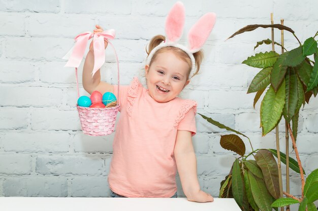 Una piccola ragazza sorridente tiene un cesto di uova di Pasqua Easter