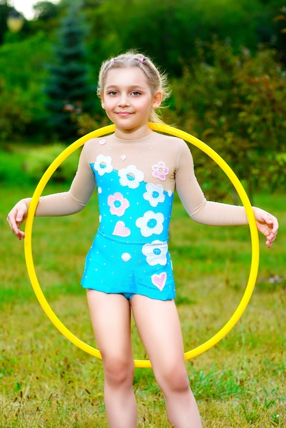 Una piccola ragazza sportiva che si esercita con l'hula hoop sopra il parco