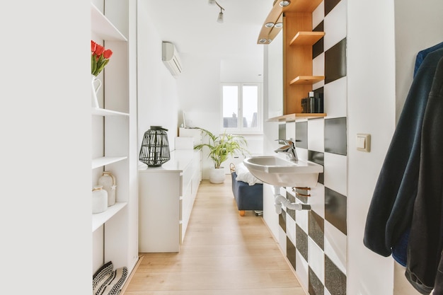 Una piccola stanza con molti scaffali, un lavandino e pavimenti in legno in una casa moderna
