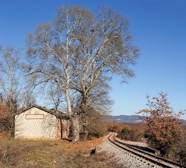Una piccola stazione ferroviaria in campagna ai piedi delle montagne in una soleggiata giornata autunnale