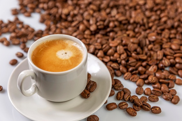 Una piccola tazza di caffè bianca si trova sui chicchi di caffè. Piacere fragrante.