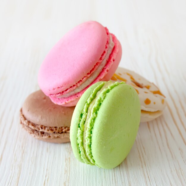 Una pila di amaretti francesi tradizionali variopinti del dessert sulla tavola di legno bianca.