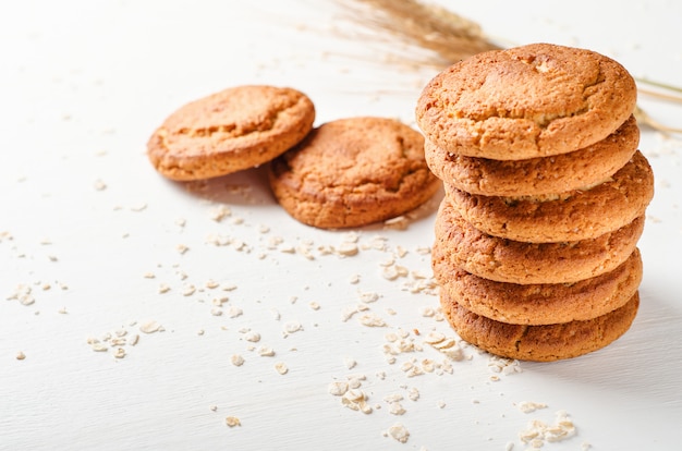 Una pila di biscotti di farina d&#39;avena con fiocchi d&#39;avena su un tavolo di legno bianco