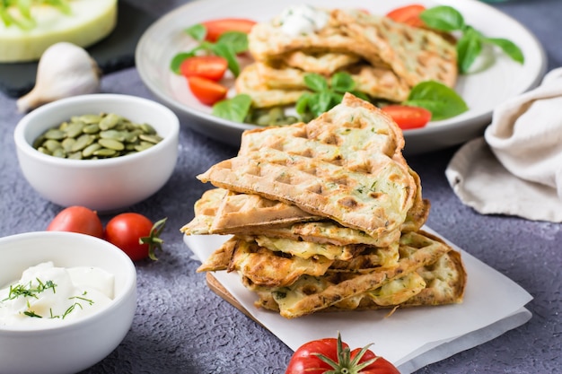 Una pila di cialde di zucchine e basilico pronte su carta da forno sul tavolo. Cibo vegetariano dietetico vegetale.