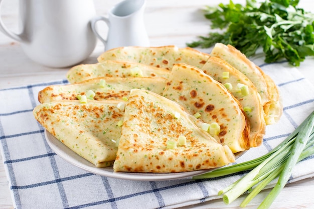 Una pila di frittelle con aneto fresco e cipolle su un piatto bianco Frittelle russe tradizionali per Maslenitsa