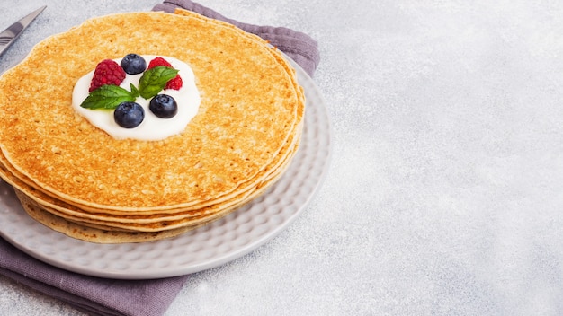 Una pila di frittelle sottili su un piatto bianco