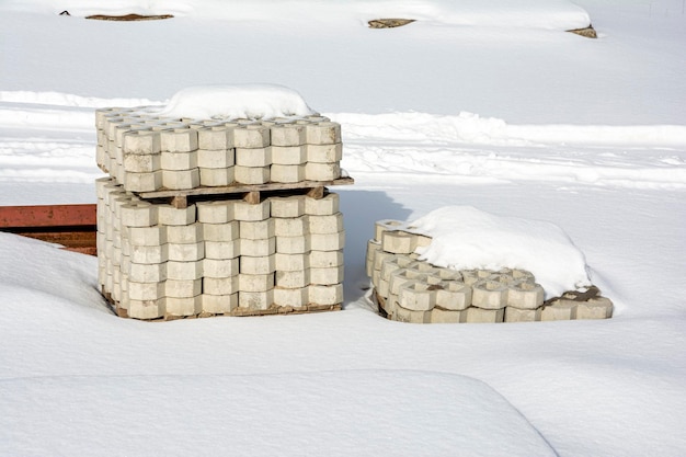 Una pila di lastre per pavimentazione in un cantiere coperto di neve