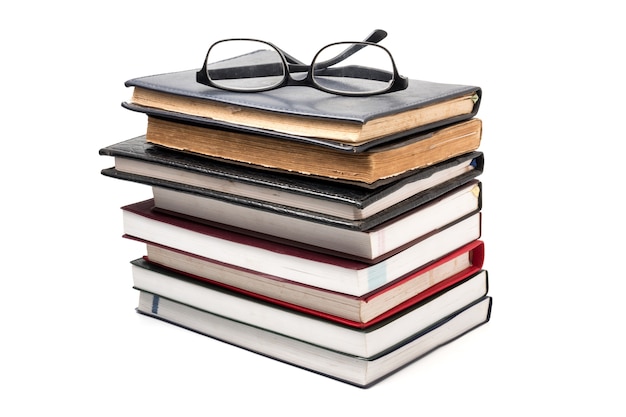 Una pila di libri con gli occhiali su uno sfondo bianco.