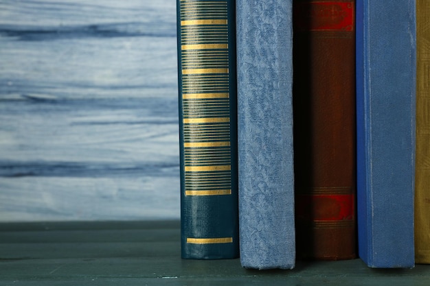 Una pila di libri su un tavolo di legno sullo sfondo blu di una parete di legno