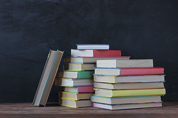 Una pila di libri su una lavagna di scuola. Di nuovo a scuola. Libri di testo nella copertina colorata sul tavolo.